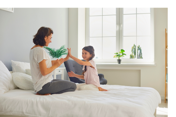 mother and daughter clapping hands on bed